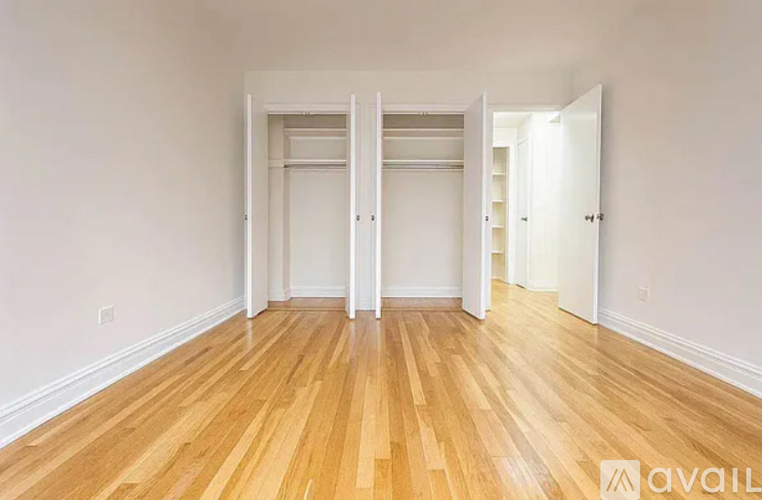 A room with wooden floors and white walls, with two open doors.