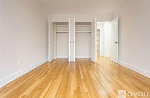 A room with wooden floors and white walls, with two open doors.