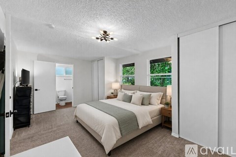 A bedroom with a large bed and a view of trees outside the window.