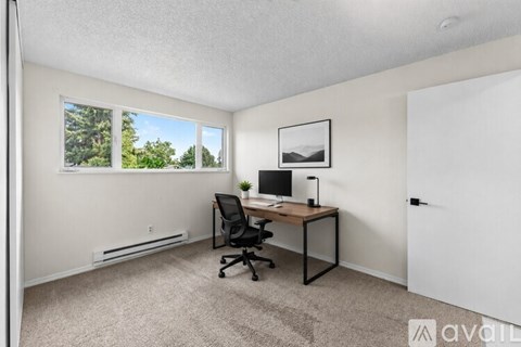 A room with a desk and a window showing trees outside.