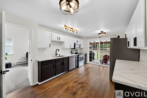 A kitchen with white cabinets and a wooden floor.
