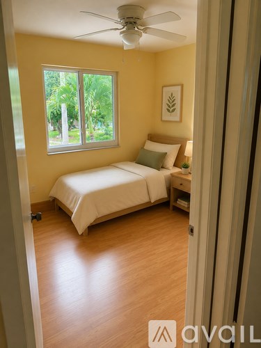 A bedroom with a bed, nightstand, and window.