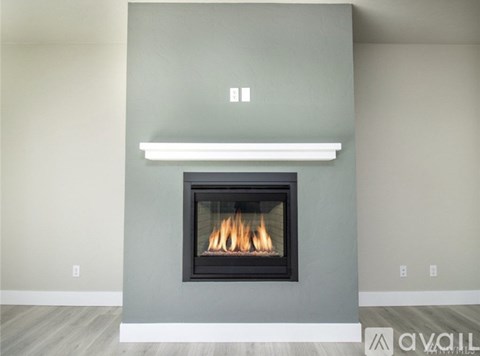 A modern fireplace with a white mantle and a grey wall.