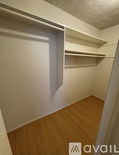 A small, empty room with a wooden floor and white walls.