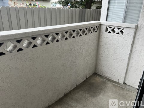 A white wall with a lattice design on top and a window with a white frame.