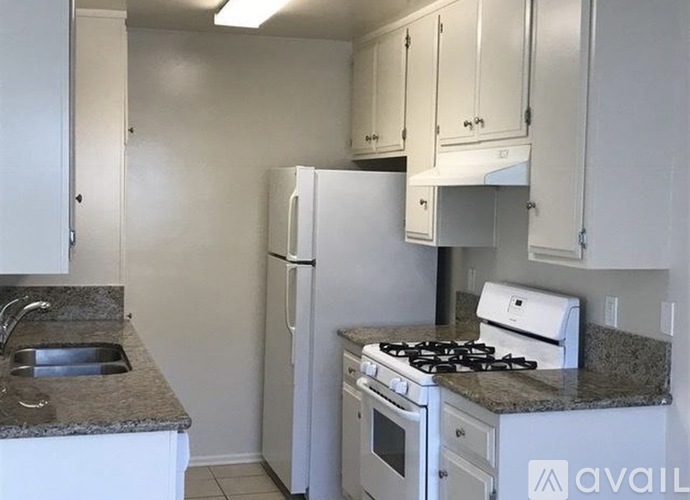 A kitchen with a white refrigerator, stove, and cabinets.