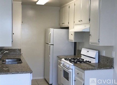 A kitchen with a white refrigerator, stove, and cabinets.