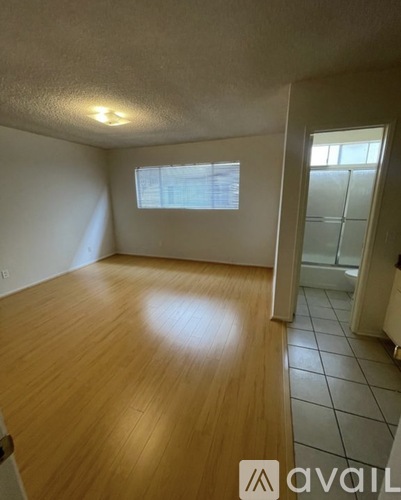 A room with wooden flooring and a window with blinds.