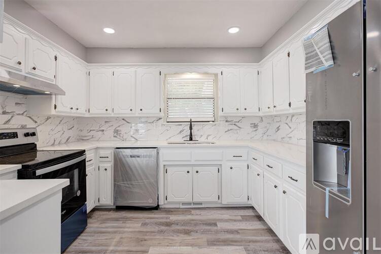 A kitchen with white cabinets and a marble backsplash.