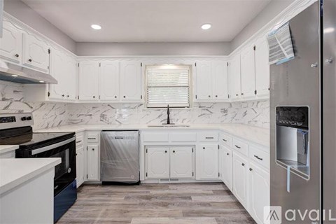 A kitchen with white cabinets and a marble backsplash.