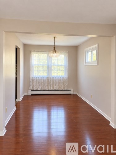 A room with wooden floors and a window with curtains.