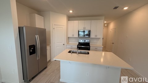 A kitchen with a refrigerator, microwave, and oven.