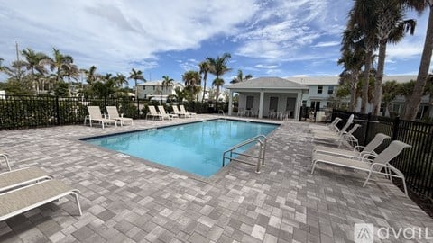A pool surrounded by lounge chairs and palm trees.
