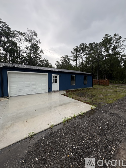 A blue garage with a white door is situated on a concrete slab.
