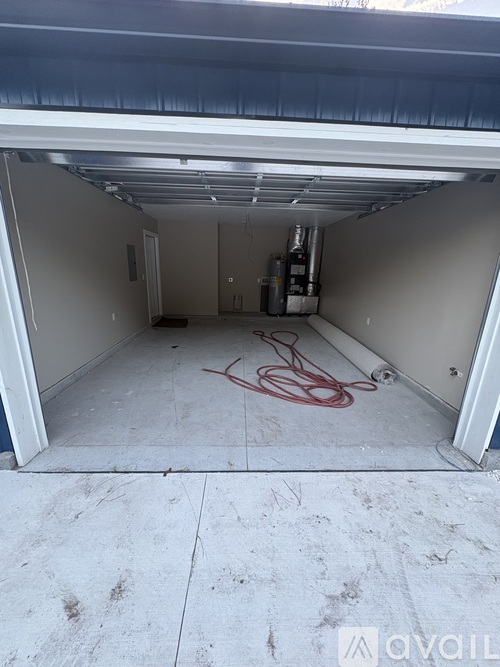 A garage with a red hose on the floor.