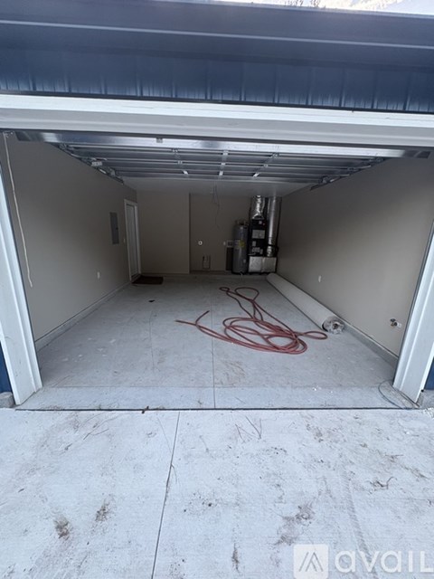 A garage with a red hose on the floor.