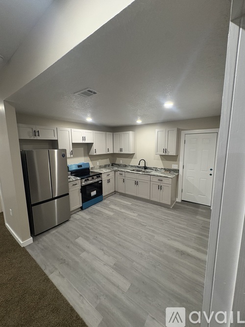 A kitchen with a stainless steel refrigerator and white cabinets.