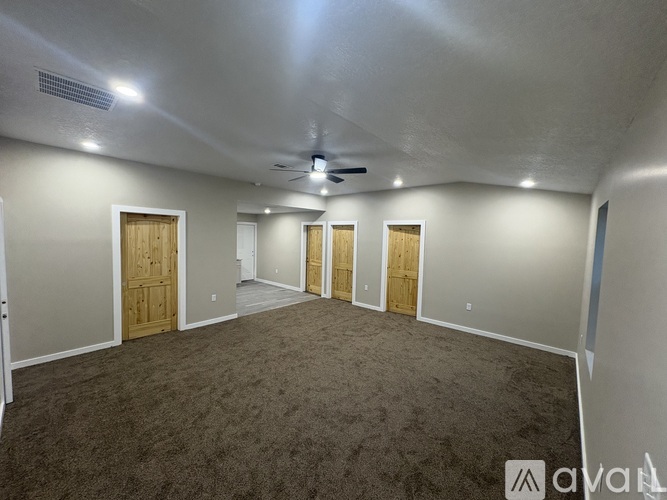 A room with carpeted floor and a ceiling fan.