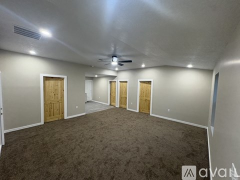 A room with carpeted floor and a ceiling fan.