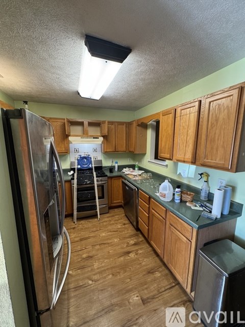 A kitchen with wooden cabinets and a stainless steel refrigerator.