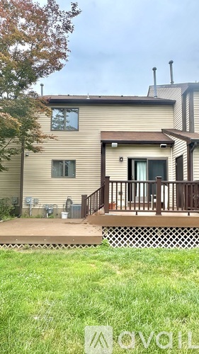 A house with a deck and a tree in front.