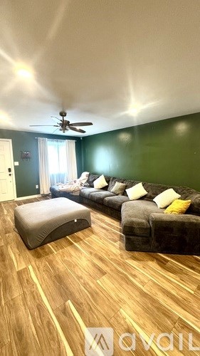 A living room with a grey couch and a wooden floor.