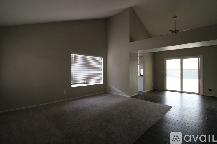 A spacious room with a carpeted floor and a ceiling fan.