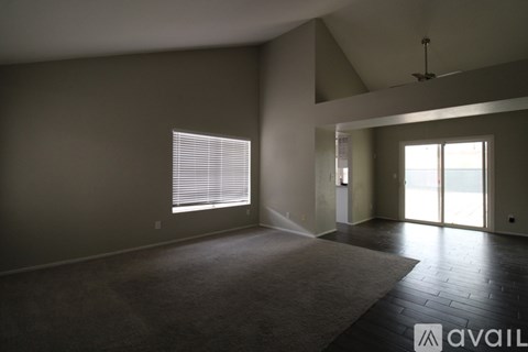 A spacious room with a carpeted floor and a ceiling fan.