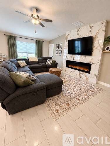 A living room with a grey sofa and a television mounted on the wall.