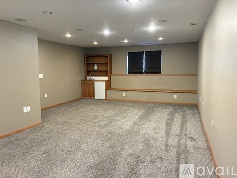 A spacious room with a carpeted floor and a window with blinds.