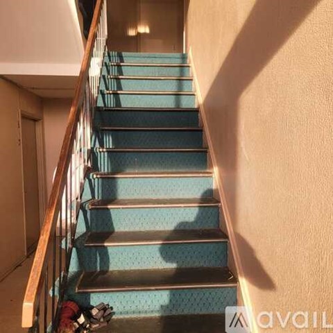 A staircase with a wooden handrail and blue treads.
