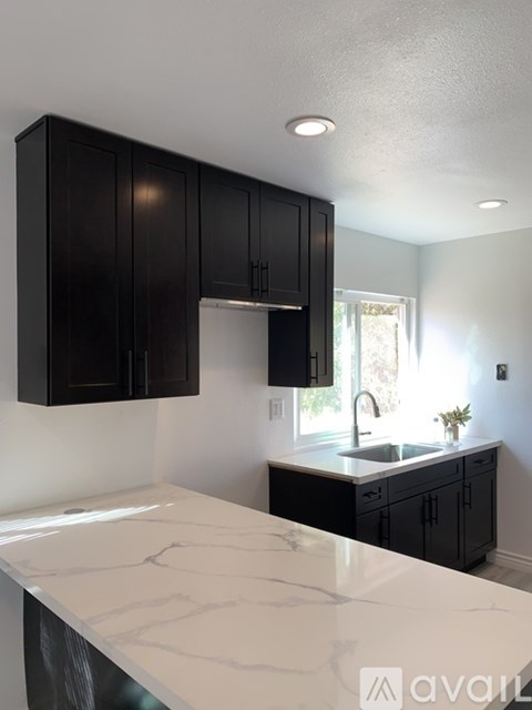 A kitchen with black cabinets and a white countertop.