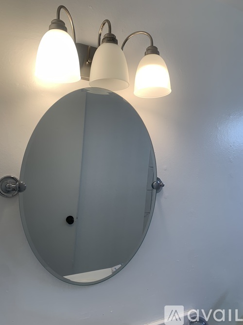 A wall-mounted mirror with three lights above it.