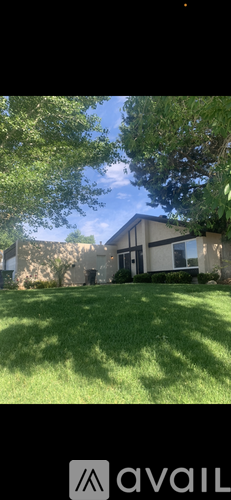 A house with a well-maintained lawn and trees in the background.