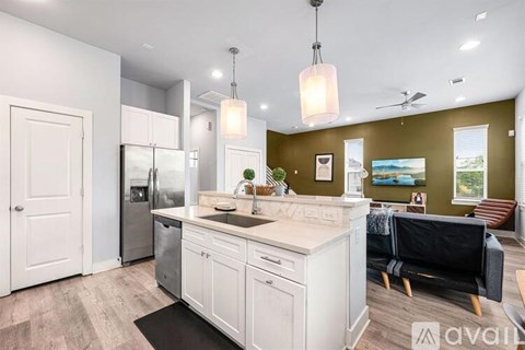 A kitchen with white cabinets and a black couch.