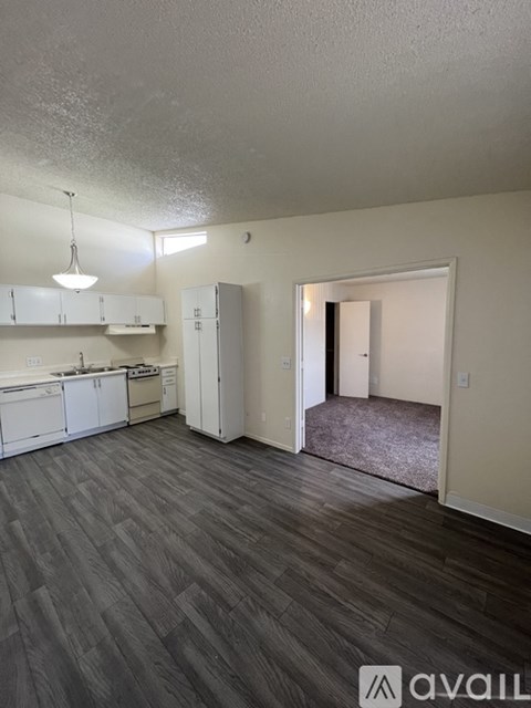 A kitchen with white cabinets and a grey floor.