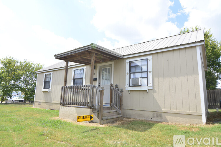 A house with a porch and a sign that says "FOR SALE".