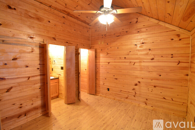 A wooden room with a ceiling fan and a window.