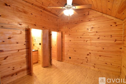 A wooden room with a ceiling fan and a window.