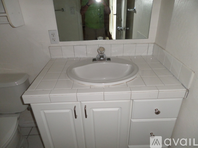 A white bathroom with a sink, toilet and a mirror.
