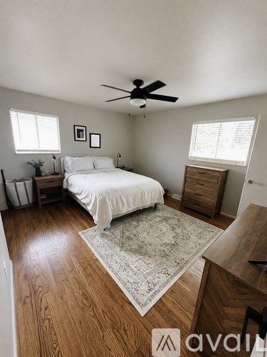 A bedroom with a bed, dresser, and ceiling fan.