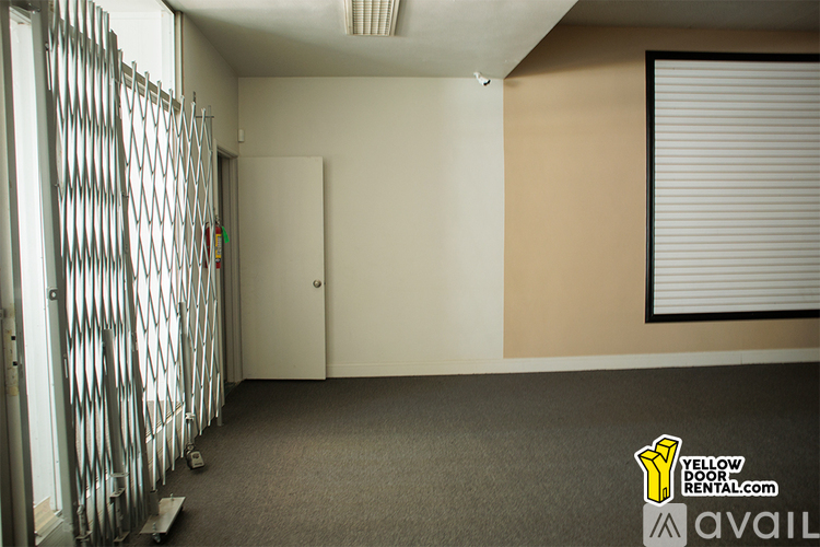 A room with a carpeted floor, a sliding door, and a closed shuttered window.