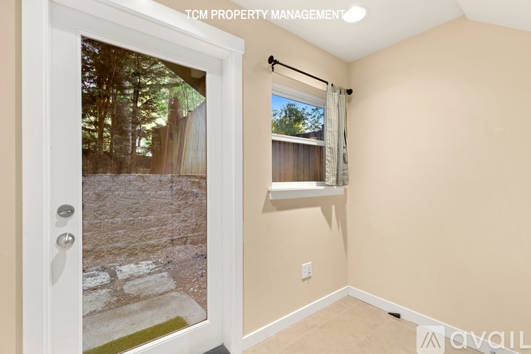 A room with a door leading outside and a window with a view of trees.