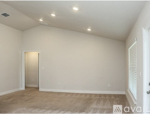 A spacious room with a carpeted floor and a door on the left side.