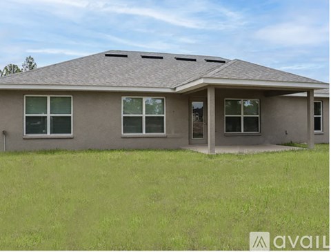 A house with a grey roof and a grassy field in front.
