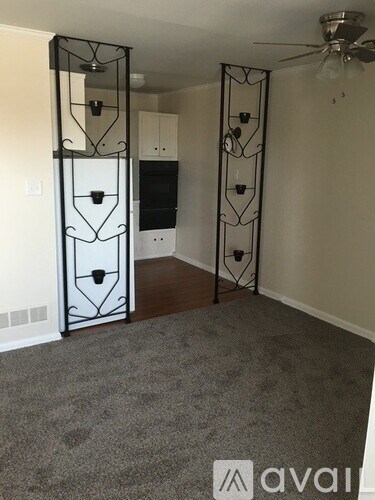 A room with a fan, a cabinet, and a decorative iron gate.
