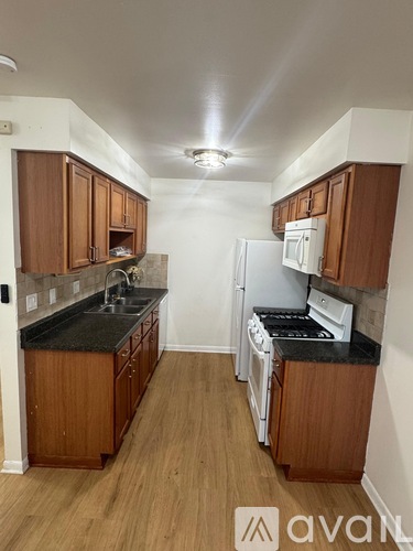 A kitchen with wooden cabinets and black countertops.