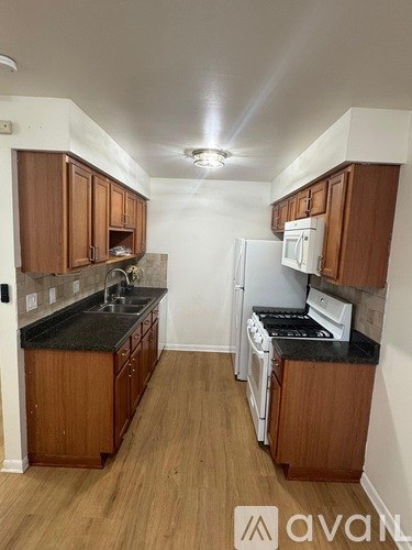 A kitchen with wooden cabinets and black countertops.