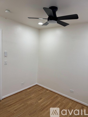 A room with a ceiling fan and wooden flooring.