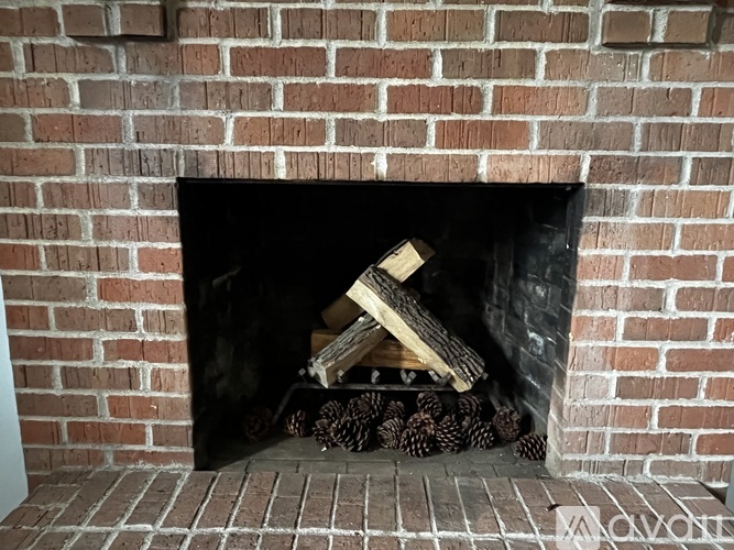 A fireplace with a pile of wood and logs inside.
